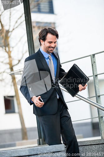 Image of Smiling businessman walking down stairs