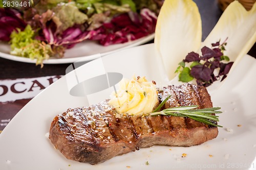 Image of Grilled beef steak topped with butter and rosemary