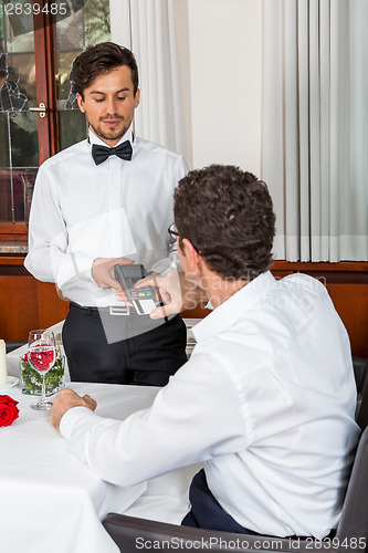 Image of Waiter happily accommodating couple