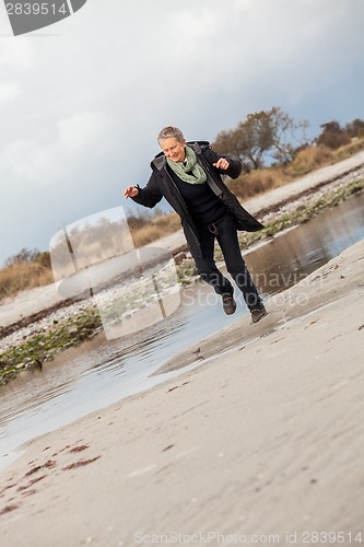 Image of Happy senior woman frolicking on the beach