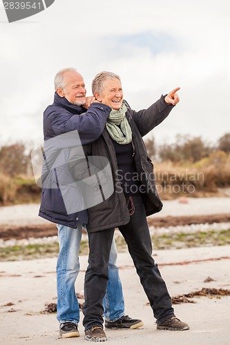 Image of happy elderly senior couple walking on beach