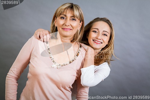 Image of smiling middle-aged young mother and daughter