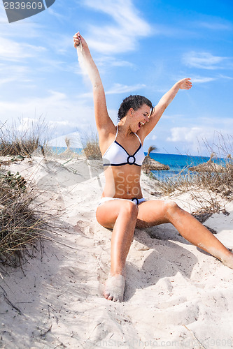 Image of Beautiful woman sitting on golden beach sand