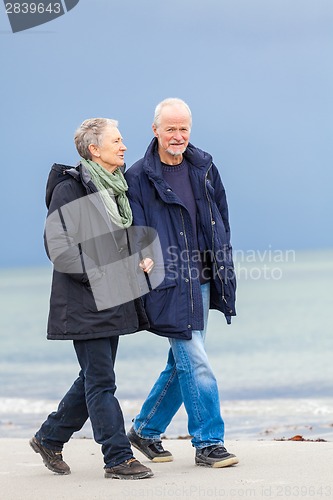 Image of happy elderly senior couple walking on beach