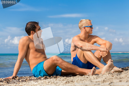 Image of Two handsome young men chatting on a beach