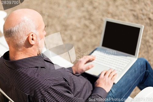 Image of Man sitting on a bench using a laptop