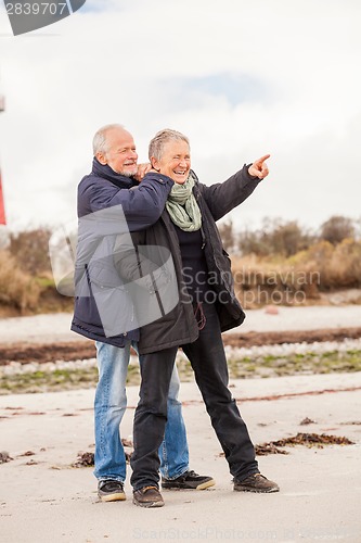 Image of happy elderly senior couple walking on beach