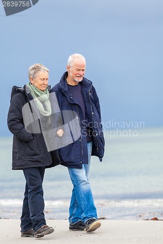 Image of happy elderly senior couple walking on beach