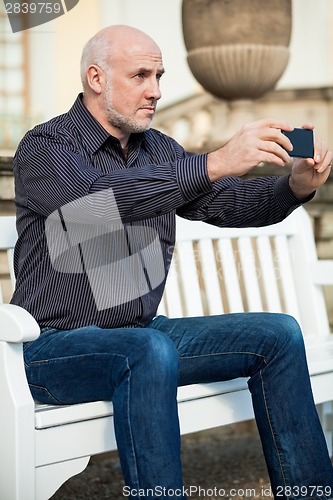 Image of Man taking a photograph with his mobile