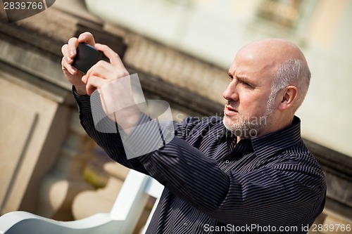 Image of Man taking a photograph with his mobile