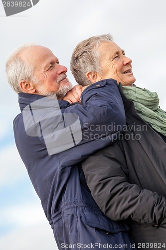 Image of happy elderly senior couple walking on beach