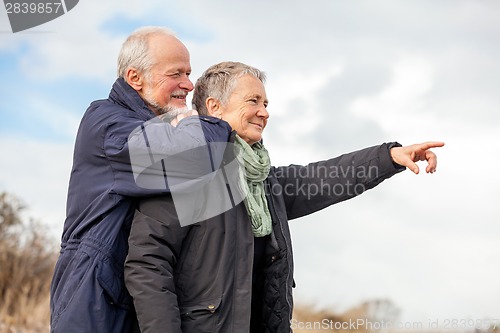 Image of happy elderly senior couple walking on beach