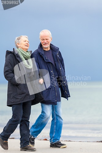 Image of happy elderly senior couple walking on beach