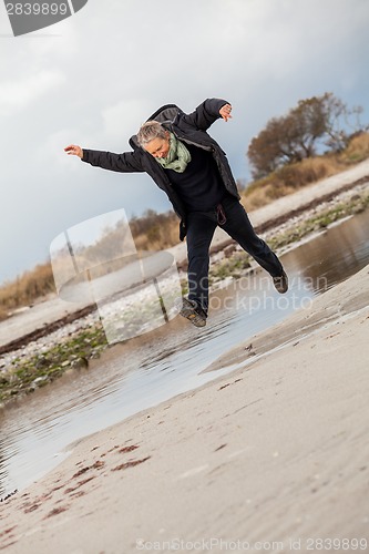 Image of Happy senior woman frolicking on the beach