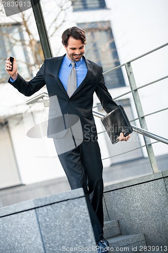 Image of Smiling businessman walking down stairs