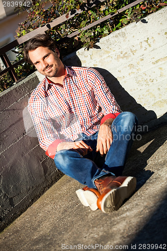 Image of Man sitting on the ground with feet crossed