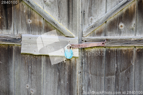 Image of wooden barn door with iron  blue lock hanging 