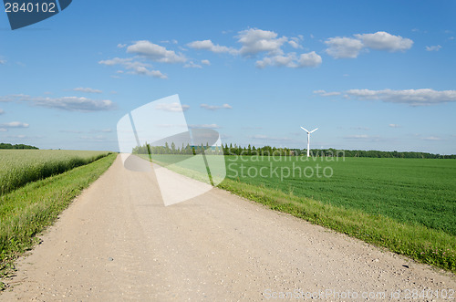 Image of Rural gravel road near fields and windmill 
