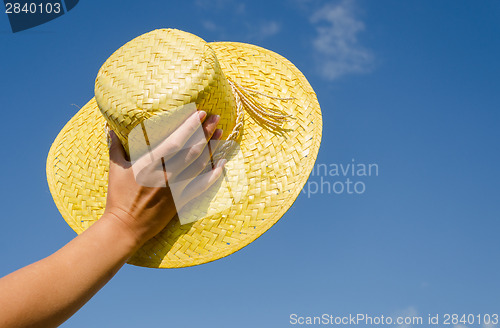 Image of hand hold yellow straw hut on blue sky background 