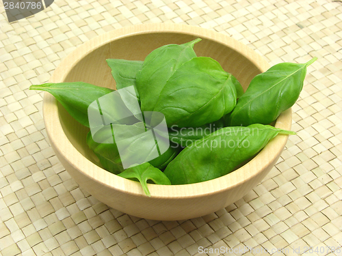 Image of Wooden bowl with basil on rattan underlay