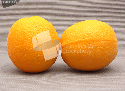 Image of Two oranges in front of a gray background