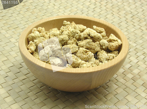 Image of Wooden bowl with soy granules on rattan underlay