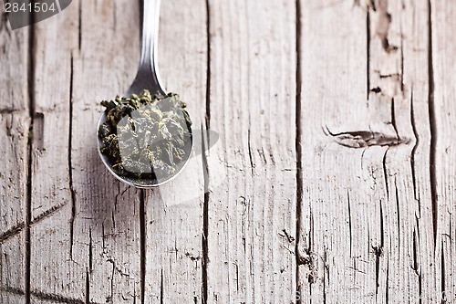 Image of spoon with dried green tea leaves 