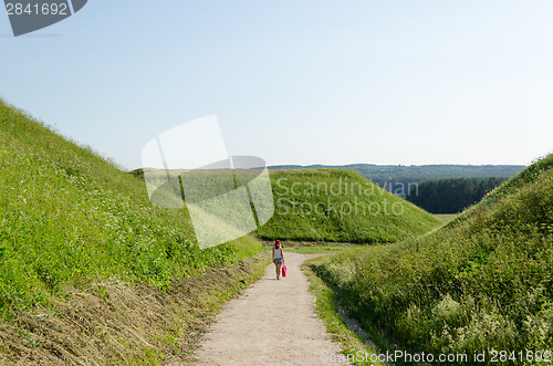 Image of tourist girl walk mound hills in Kernave 