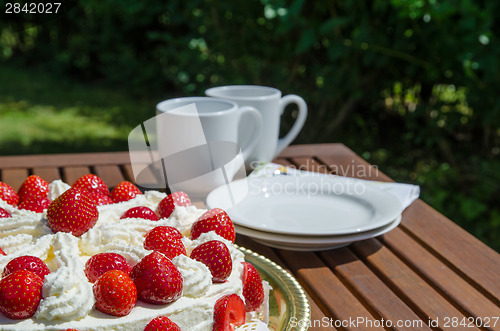 Image of Table with strawberry cake and coffee cups in background