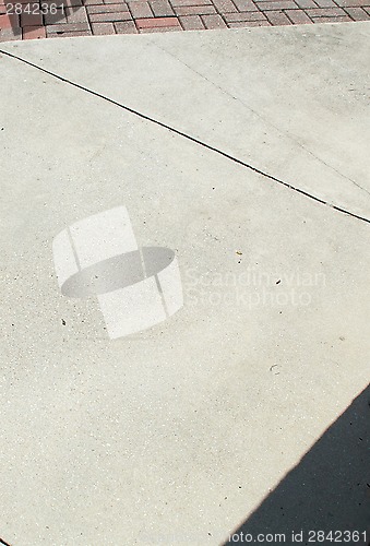 Image of cement sidewalk with brick and shadow