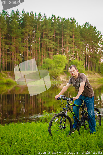 Image of Young man on the GT bicycle biking through a sunny countryside. 