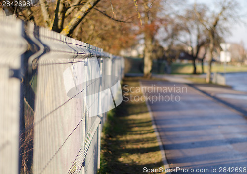 Image of iron rods fence along paved path 