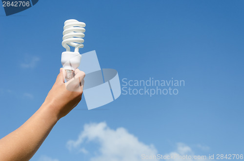 Image of hand hold energy saving lamp blue sky background 