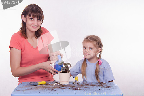 Image of Mom and daughter watered transplanted flower room