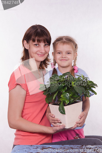 Image of Mom and daughter with a potted flower in hands