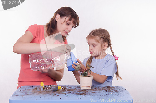 Image of Mom and daughter poured water into a watering can flowers