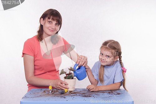 Image of Mom and daughter watering potted flower room