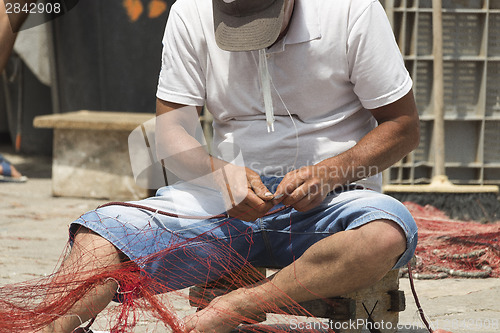 Image of Fisherman repairs his net