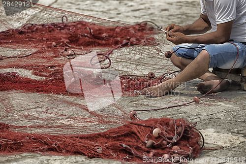 Image of Fisherman repairs his net
