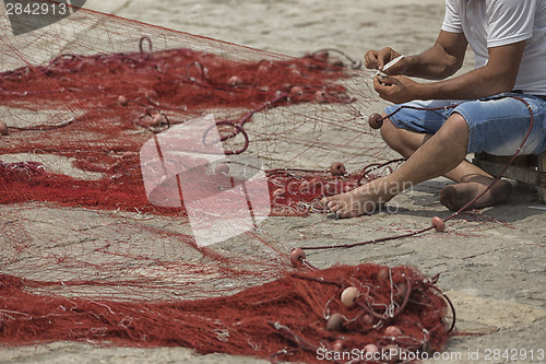 Image of Fisherman repairs his net