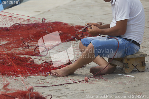 Image of Fisherman repairs his net