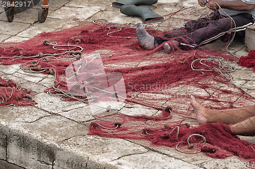 Image of Fisherman repairs his net