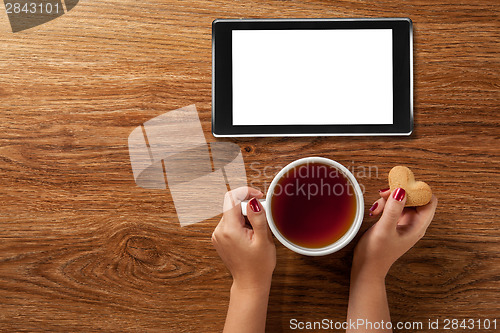 Image of woman holding hot cup of tea with cookies