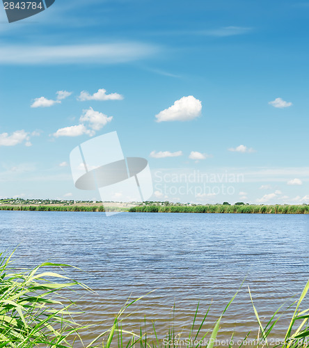 Image of river with green coast and clouds in blue sky