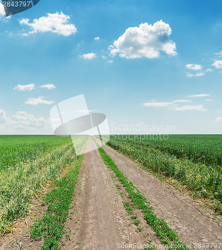 Image of empty countryside road with green grass and clouds