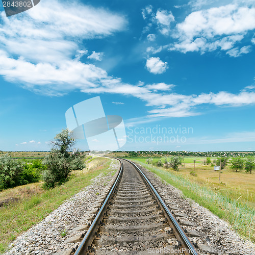 Image of railway in green landscape and white clouds in blue sky