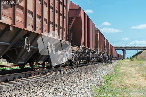 Image of wagons of a freight train in motion go to horizon under bridge