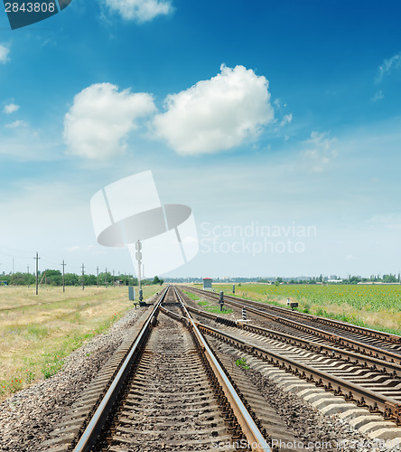 Image of crossing of two railroads and blue sky with clouds