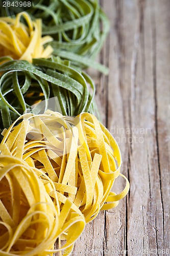 Image of yellow and green uncooked pasta tagliatelle 