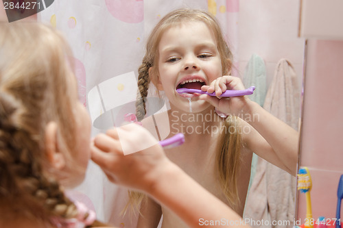 Image of Five-year girl brushing her teeth in bathroom